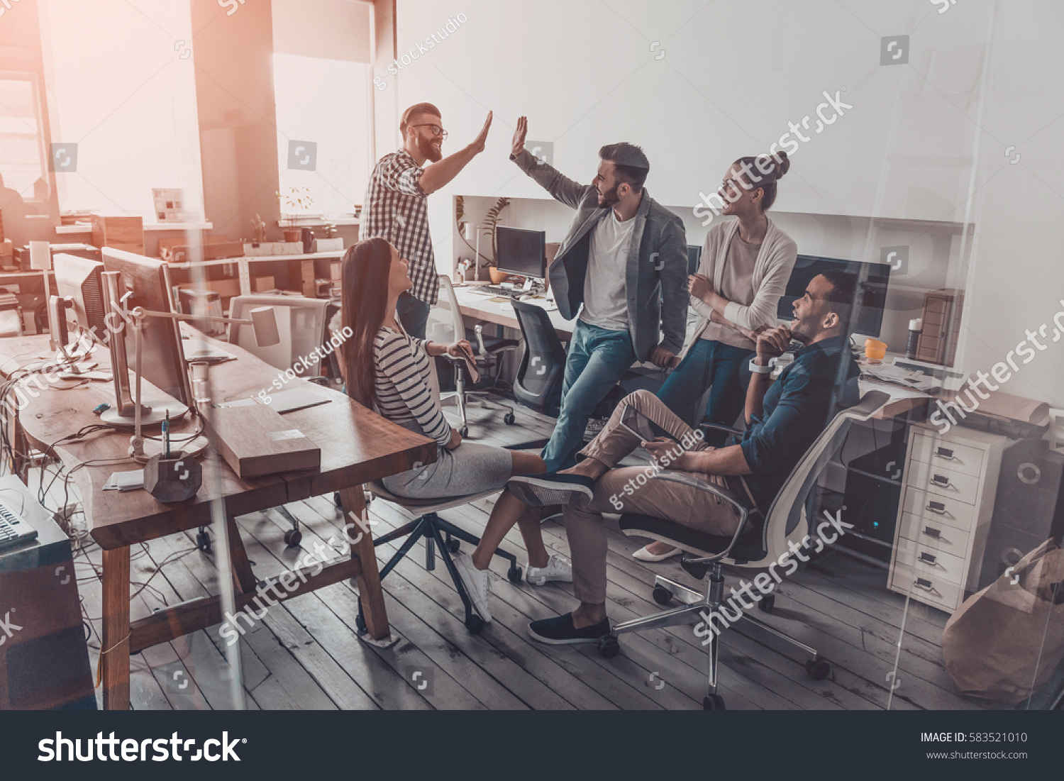 stock-photo-we-did-it-two-cheerful-young-business-people-giving-high-five-while-their-colleagues-looking-at-583521010.jpg