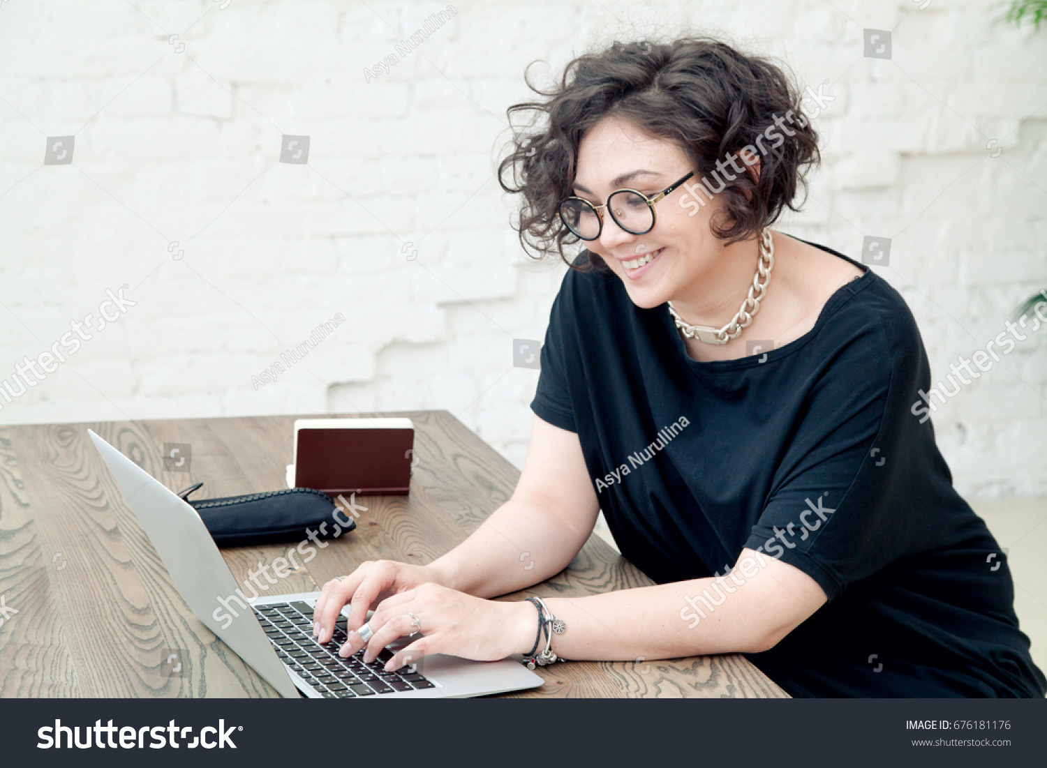 stock-photo-young-plus-size-female-model-sitting-in-front-of-the-table-smiling-and-working-on-her-notebook-676181176.jpg